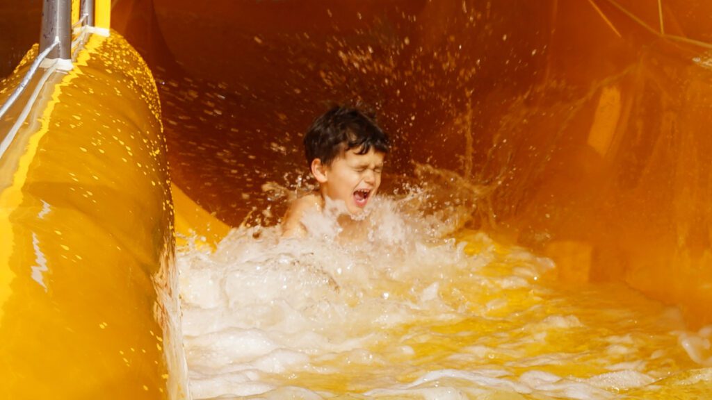 Young boy coming out of water slide