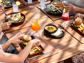 A girl eating a burger at a restaurant with adult family members at Hilton Cancun, an All-Inclusive Resort
