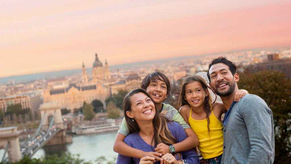 Family hugging each other on top of hill with historic city in the background during sunset