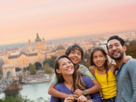 Family hugging each other on top of hill with historic city in the background during sunset