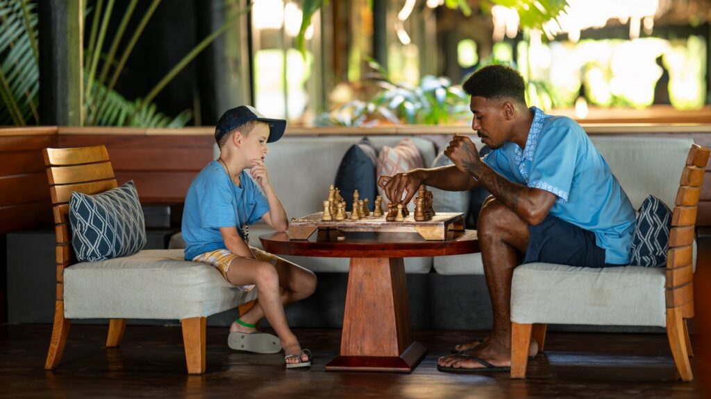 A boy playing chess with his buddy at Jean-Michel Cousteau Resort