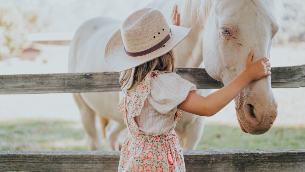 A girl petting a white horse at Alisal Ranch