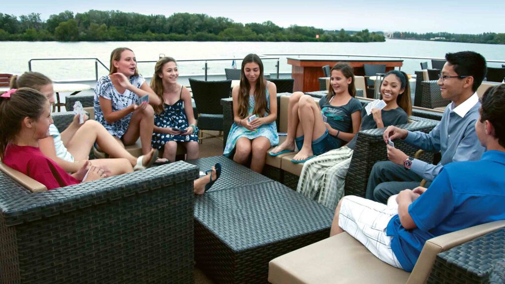 Teenagers gathering around a table on a river cruise pool deck