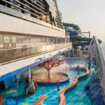 Side of cruise ship with water park at sunset