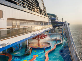 Side of cruise ship with water park at sunset