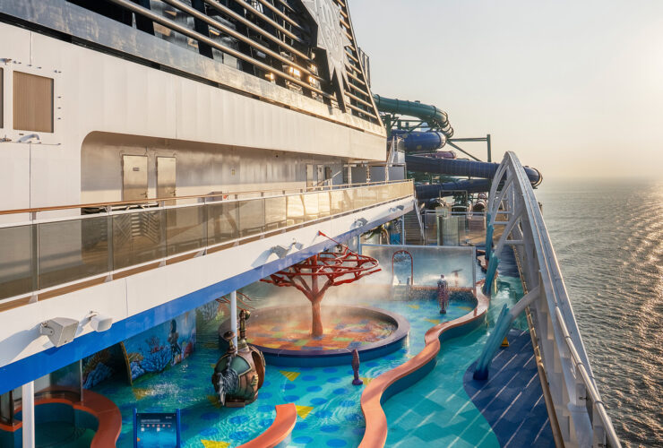 Side of cruise ship with water park at sunset