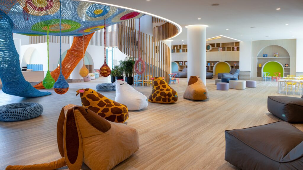 A kids club space with chairs that look like giraffes and other animals and and a colorful climbing area