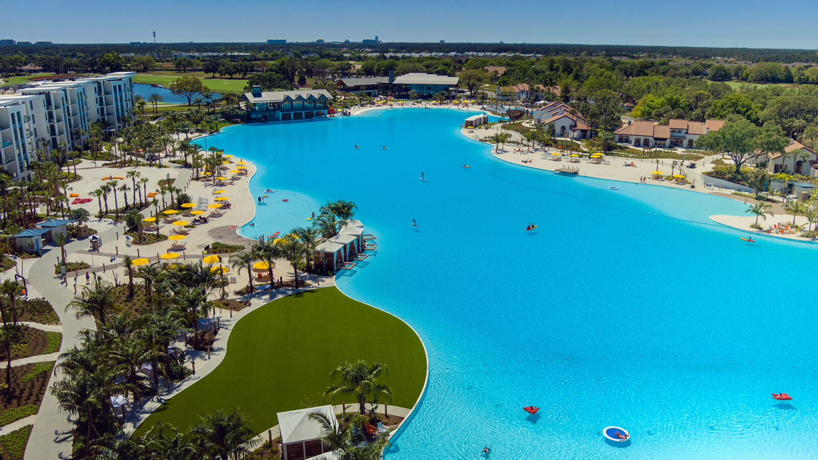 Sprawling lagoon surrounded by grassy lawns, small beaches and buildings