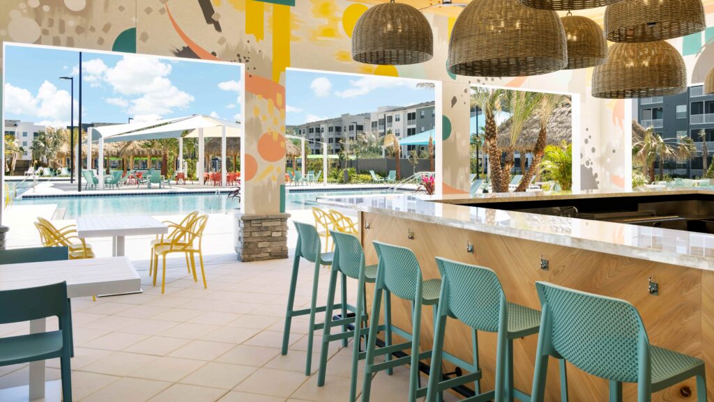 A restaurant by the pool with a bar with turquoise stools and wicker lighting lights above the Villel Orlando Resort