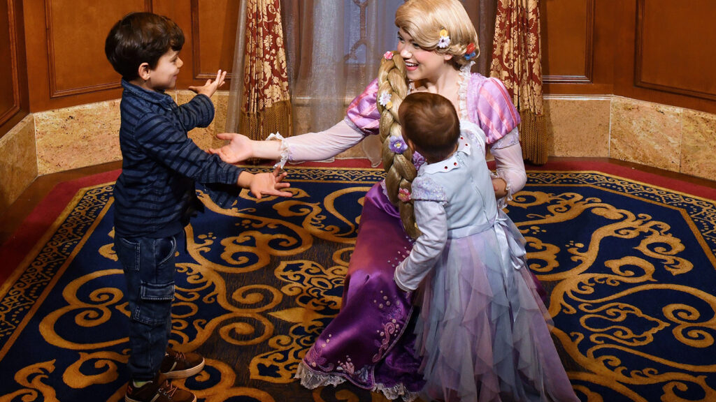 Two young children gleefully meeting a princess character