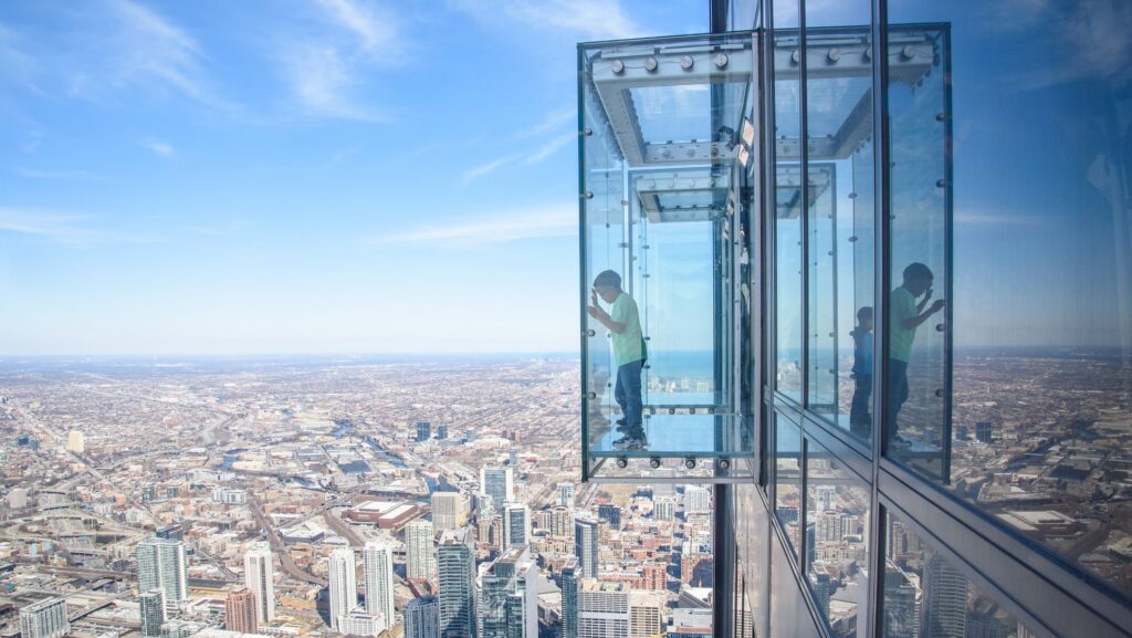 Two boys looking down from a glass outlook at Skydeck in Chicago