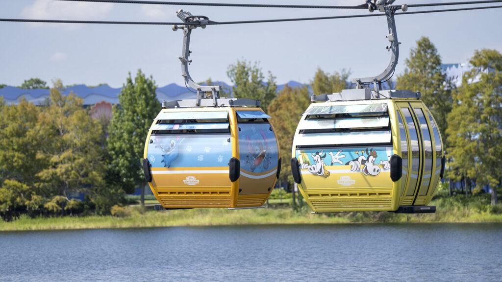 Two gondolas running along cables in the air above a lake