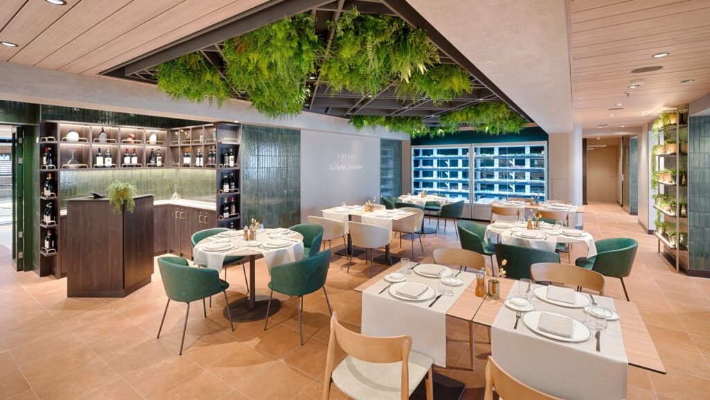 Dining tables under a ceiling plated with greenery at Eataly on MSC World America