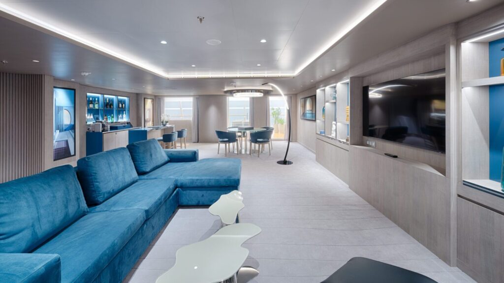A living and dining areas decorated in shades of blue in the MSC Yacht Club on MSC World America