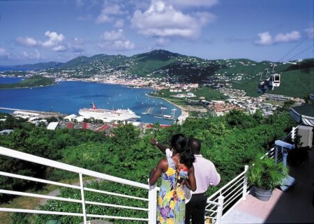 Couple standing on hill overlooking a bay with cruise ship and mountains in the background