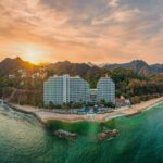 Hotel on mountainous coastline at sunset
