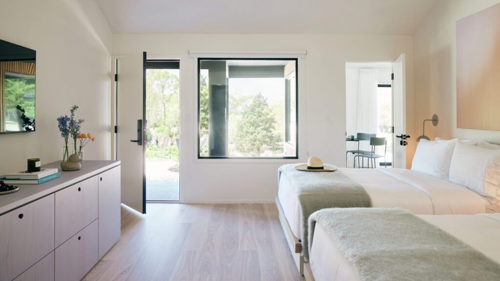 Interior of a guest room with two beds and natural hued decor at Three Ducks Westhampton