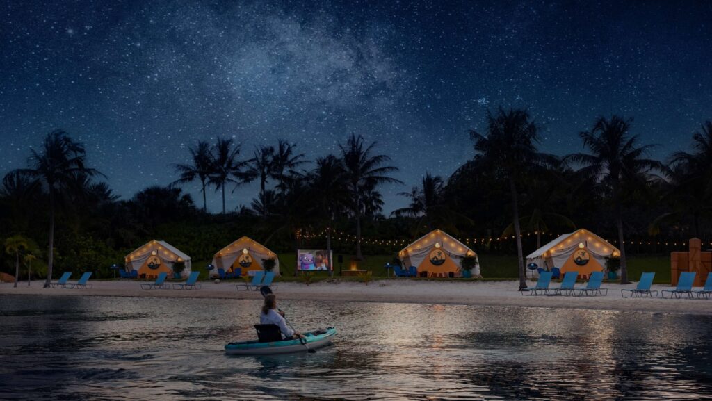 A woman paddling under the moonlight by tents at the water's edge at Atlantis
