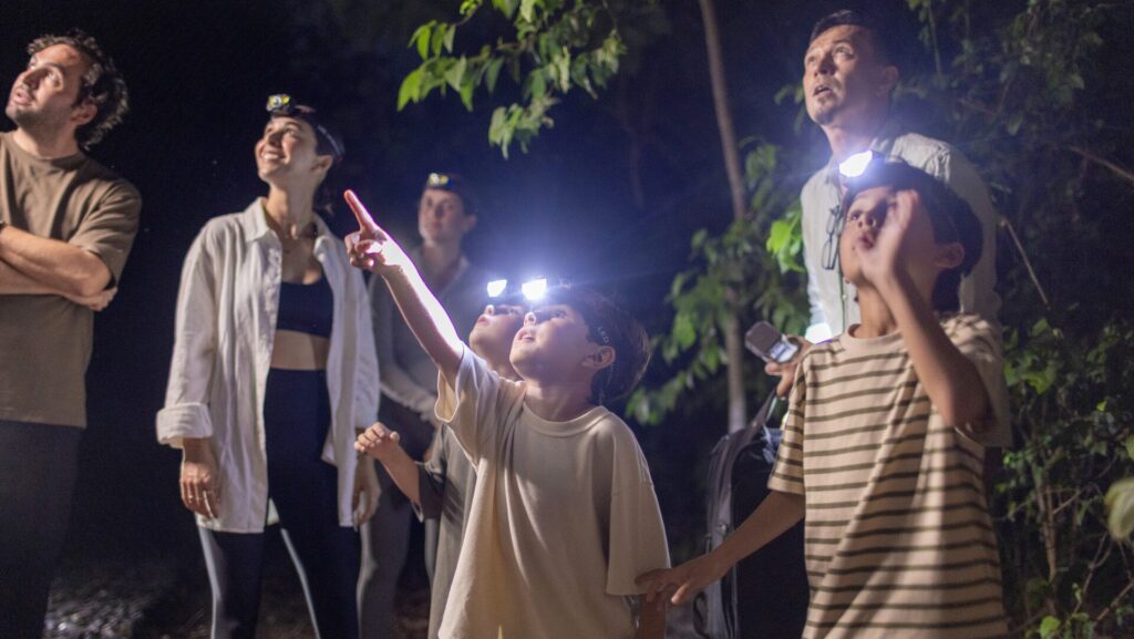 Kids and adults wearing headlamps on a nighttime excursion at Four Seasons Resort Tamarindo