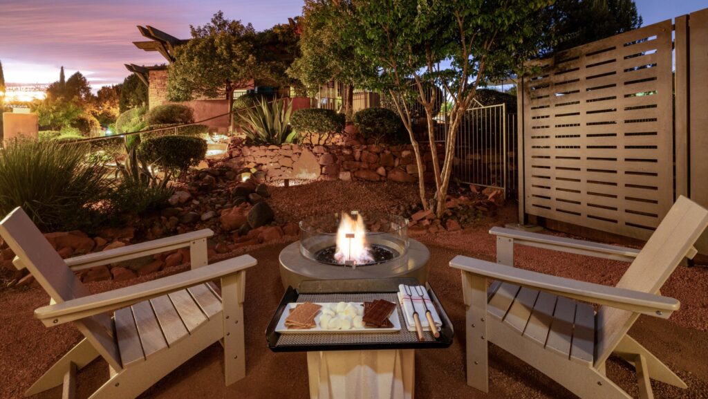 Two Adirondack chairs around a fire pit with s'mores at sunset at Hilton Sedona Resort