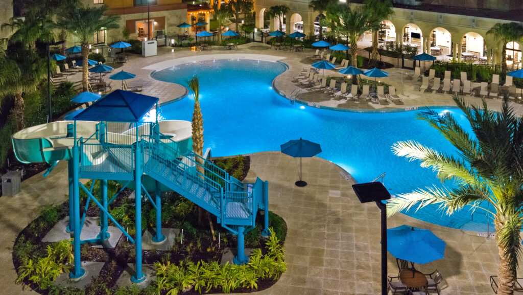 A nighttime view of the pool and waterslide at Homewood Suites by Hilton Orlando at Flamingo Crossings Town Center