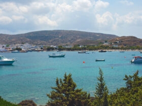 Fishing boats anchored in bay with mountains and small village in background