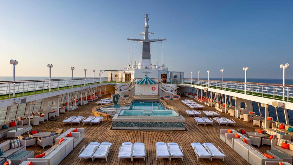 Cruise ship pool deck surrounded by padded lounge chairs