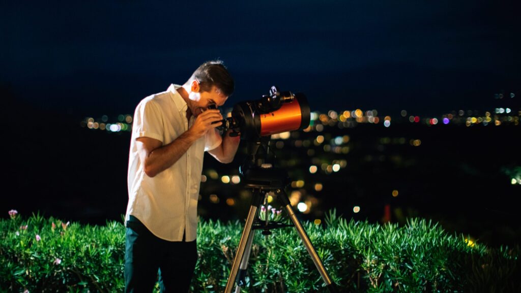 A man looking through a telescope at night at ADERO Scottsdale Resort