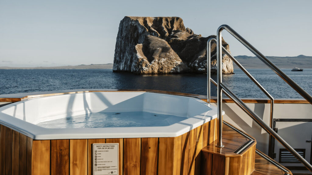 Hot tub on cruise deck with sea and rocky landscape in background