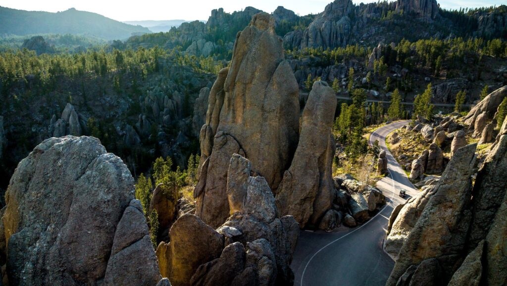 A car driving along Needles Highway past needle-like granite formations at Custer State Park