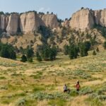 A family hiking through a field with rocky cliffs behind them at Fort Robinson State Park