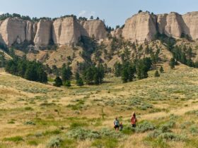 A family hiking through a field with rocky cliffs behind them at Fort Robinson State Park