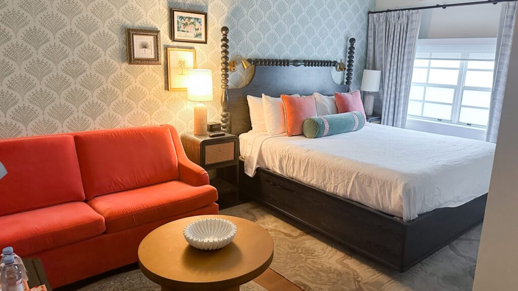 A king bed and orangish couch in a room in the Avalon house at Southernmost Beach Resort
