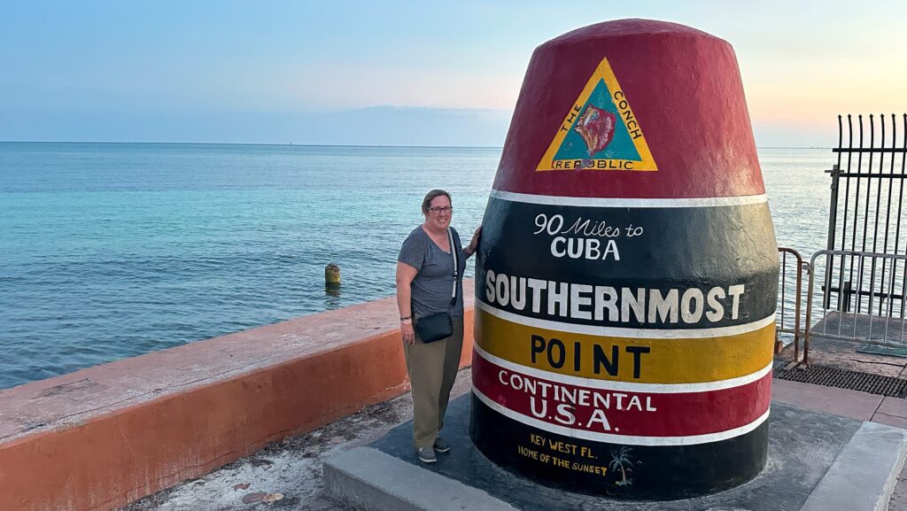 Writer Beth Luberecki poses by the Southernmost Point Buoy in Key West around sunset