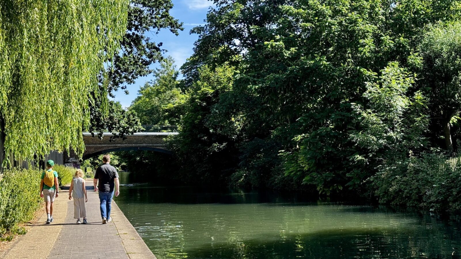 family walking along a London canal in summer on a sunny day