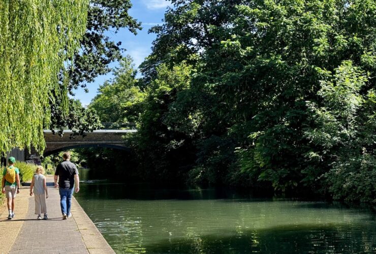 family walking along a London canal in summer on a sunny day