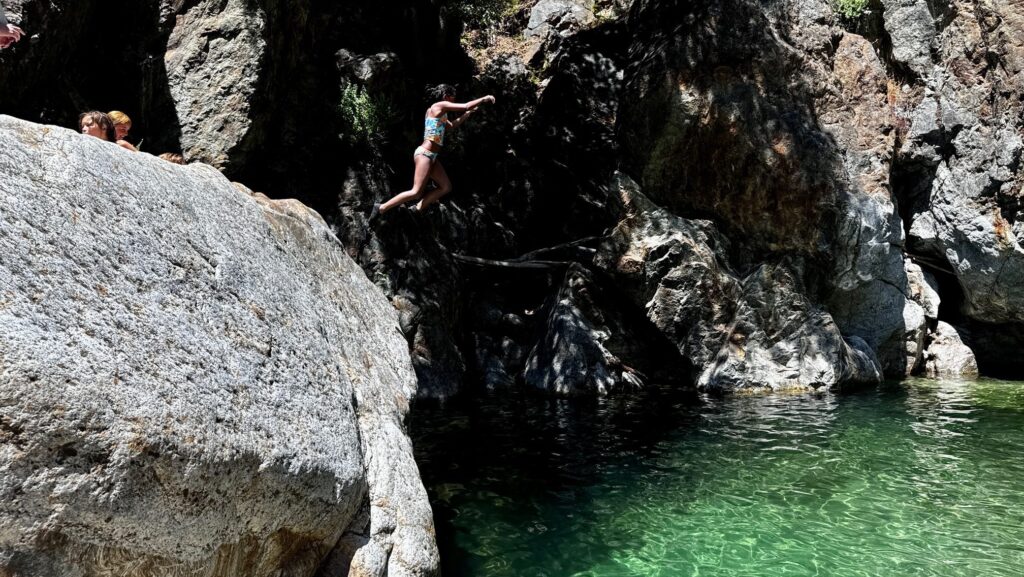A girl jumping from a rock into the water at Julia Pfeiffer Burns State Park