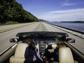 Two people in a convertible driving down Great River Road in Illinois
