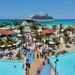 Cruise ship docked at island with many buildings and a pool in the foreground