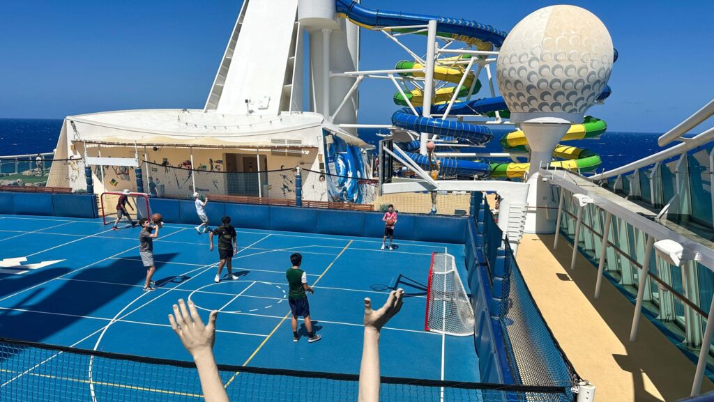 Kids playing on a sports court with waterslides behind them on a Royal Caribbean cruise ship