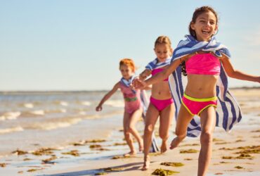 Three kids running on the beach at Ocean Edge Resort & Golf Club