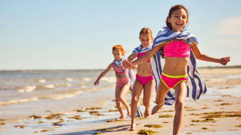 Three kids running on the beach at Ocean Edge Resort & Golf Club
