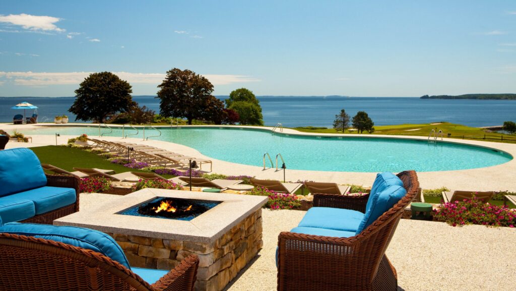 Chairs by a firepit overlooking the pool and lake at Samoset Resort