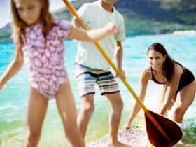A mom pushing two kids on a paddleboard at The Royal Sonesta Kauaʻi Resort