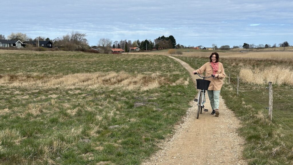 Author Alliison Tibaldi pushing a bike along a path in the Danish Riviera in shoulder season