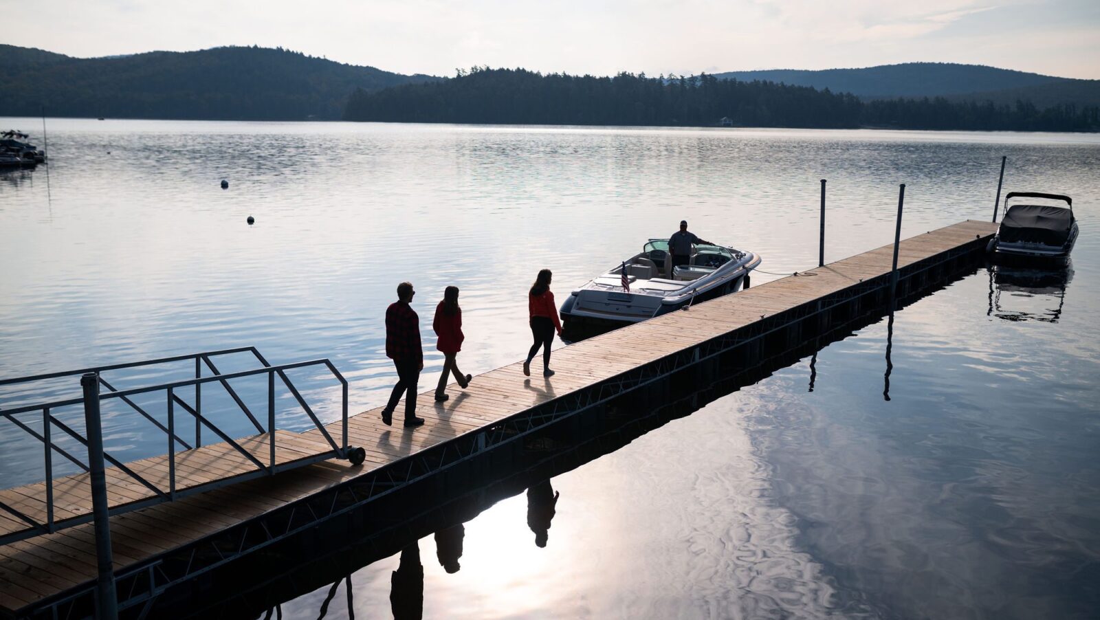 people walking along a dock toward a waiting boat at the Lodge at Schroon Lake during the quiet shoulder season