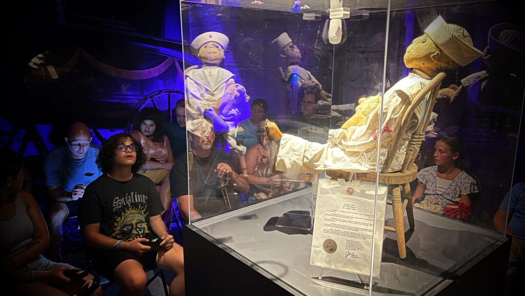 Visitors looking at Robert the Doll sitting in a case at the Fort East Martello Museum in Key West