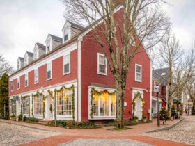 A red building on a cobblestone street decorated for Christmas in Nantucket, MA