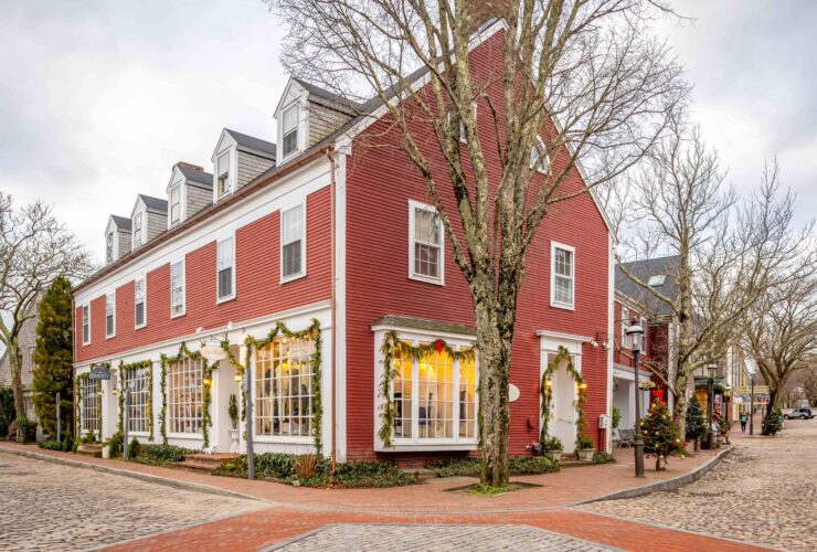 A red building on a cobblestone street decorated for Christmas in Nantucket, MA