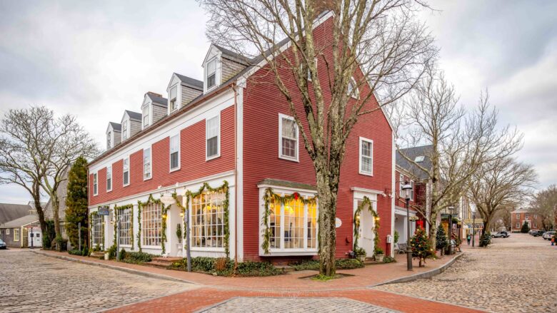 A red building on a cobblestone street decorated for Christmas in Nantucket, MA
